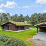 Modern wooden cabin with green roof and garage in the woods.