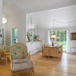Living and dining area with hardwood floor, seating, and garden view.