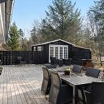 Terrasse mit Tisch und Stühlen, Grill und Sitzgelegenheiten vor einem Holzhaus in Waldnähe.