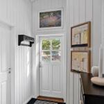 Haus-Eingang mit weißen Wänden, Tür und Bildern an der Wand.