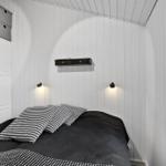 Schlafzimmer mit Bett, Schrank und Fenster. Wände sind weiß verkleidet.