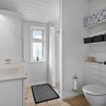 Badezimmer mit Waschbecken, Toilette, Dusche und Regalen mit Handtüchern.