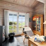 Wohnzimmer mit Holzwand, Kamin und Glasfront zum Garten.