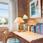Holzgetäfelte Wand mit Schreibtisch, Lampe und Bücherregal. Fenster mit Blick auf Grün.