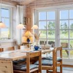Esszimmer mit Holztisch, Stühlen und Blick auf Grünflächen.