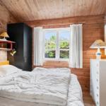 Schlafzimmer mit Holzwand, Bett, Schrank und Fenster mit Blick auf Grün.