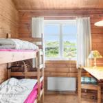 Zimmer mit Doppelstockbett, Schreibtisch und Fenster mit Blick auf Grünflächen.