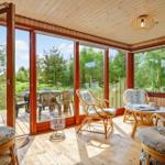 Terrasse mit Sitzgruppe und Blick auf Garten. Holzdecke und Fensterfront.