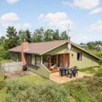 Grünes Ferienhaus mit Terrasse und Garten. Sicht auf Wohnbereich und Grillplatz.
