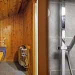 Sauna mit Holzwand und Dampfgenerator. Dusche mit Glaswand und modernem Duschkopf.