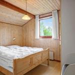 Schlafzimmer mit Holzwand, Bett und Fenster mit Blick auf Grün.