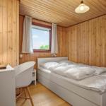 Schlafzimmer mit Holzwänden, weißem Bett und Schreibtisch mit Stuhl.