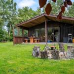 Holzhütte mit Terrasse, Grill und rustikalem Grillplatz im Grünen.