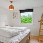 Schlafzimmer mit Doppelbett, Fenster mit Blick auf Bäume und Holzgarderobe.
