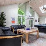 Wohnbereich mit Sofa, Tisch und Billardtisch. Große Fenster und Dachfenster.