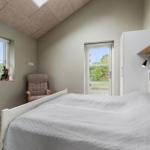 Schlafzimmer mit Bett, Sessel, Fenster und Tür. Decke mit Dachfenster.
