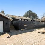 Schwarze Holzhäuser mit Garage und Terrasse unter blauem Himmel.