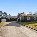 Schwarze Ferienhaus mit Garage und Basketballkorb im Freien.