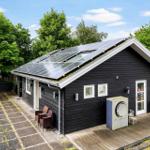 Schwarzes Haus mit Solaranlage, Terrasse und Garten. Außenbereich mit Tisch und Stühlen.