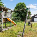 Hinterhof mit Spielplatz, Schaukel und Rutsche. Garage im Hintergrund.