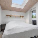 Schlafzimmer mit Dachfenster, Bett und Schrank. Fenster und Tür zur Außenseite.