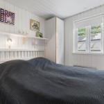 Schlafzimmer mit Bett, Wandregal und Fenster. Wände sind weiß verputzt.