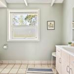 Badezimmer mit Waschbecken, Toilette und Fenster mit Blick auf Bäume.