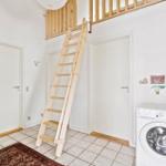Haus mit Holztreppe zur oberen Etage und Waschmaschine in einem Raum mit Fliesenboden.