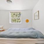Schlafzimmer mit Bett, Fenster und Stuhl.