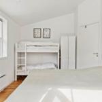 Zimmer mit Doppelbett, Etagenbett und Fenster mit Blick auf Grün.