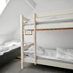 Zimmer mit Doppelstockbett und Einzelbett unter Dachschräge mit Dachfenster.