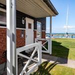 Haus mit weißer Tür und Balkon, Blick auf Hafen mit Segelbooten.