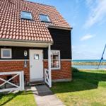 Haus mit rotem Dach, weiße Tür und Garten. Boot liegt am Wasser.