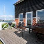 Terrasse mit Grill, Tisch und Stühlen. Blick auf Segelboote am Wasser.