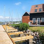 Haus mit Terrasse neben Steg und Booten im Hafen.