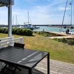 Terrasse mit Tisch und Stuhl, Blick auf Hafen mit Booten und Grünflächen.