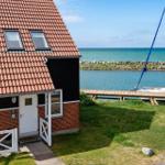 Haus mit rotem Dach und Bootssteg am Wasser.