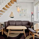 Wohnzimmer mit braunem Ledersofa, Holztisch und Stufen zur Galerie.