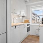 Küche mit weißen Schränken, Holzoberfläche und Fensterblick auf Außentreppe.