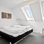 Schlafzimmer mit Dachfenstern, Bett, Stuhl und Nachttisch.