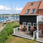 Haus mit Terrasse und Blick auf den Hafen mit Segelyachten.