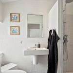Bathroom with sink, mirror, shower, and toilet. Wall art and towel hanging.