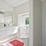 Bathroom with shower, sink, and toilet. Window with view of greenery.