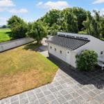 White house with terrace, garden, and view of fields and water.
