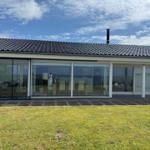 Modern villa with large glass area and terrace. View of lawn and sky.
