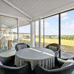 Round table with chairs under glass roof, view of lawn and horizon.