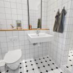 Badezimmer mit Toilette, Waschbecken und Spiegel. Fliesen an Wänden und Boden.