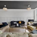 Wohnzimmer mit drei Sofas, Glas-Tisch und schwarzer Decke.