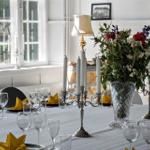 Gedeckter Tisch mit Blumen, Kerzen und Gläsern vor Fenster