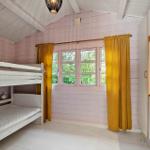 Zimmer mit Doppelstockbett, Fenster mit gelben Vorhängen und Schrank.